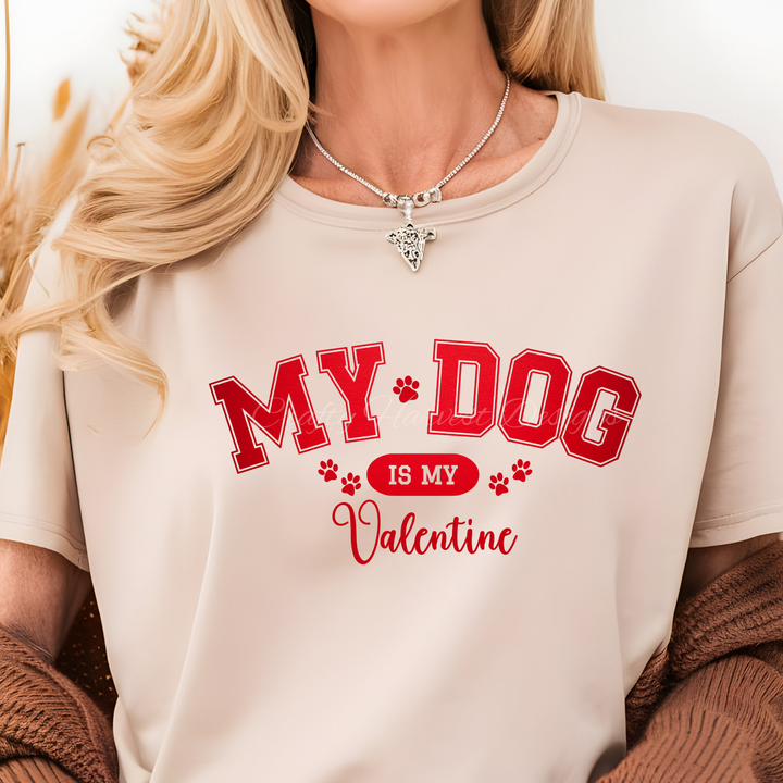 Model wearing a beige t-shirt featuring the ‘My Dog Is My Valentine’ design in red varsity-style text with paw print accents.