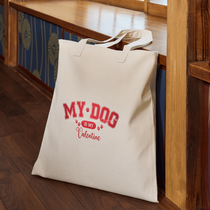 Beige tote bag featuring the ‘My Dog Is My Valentine’ design in red varsity-style text with paw print accents.